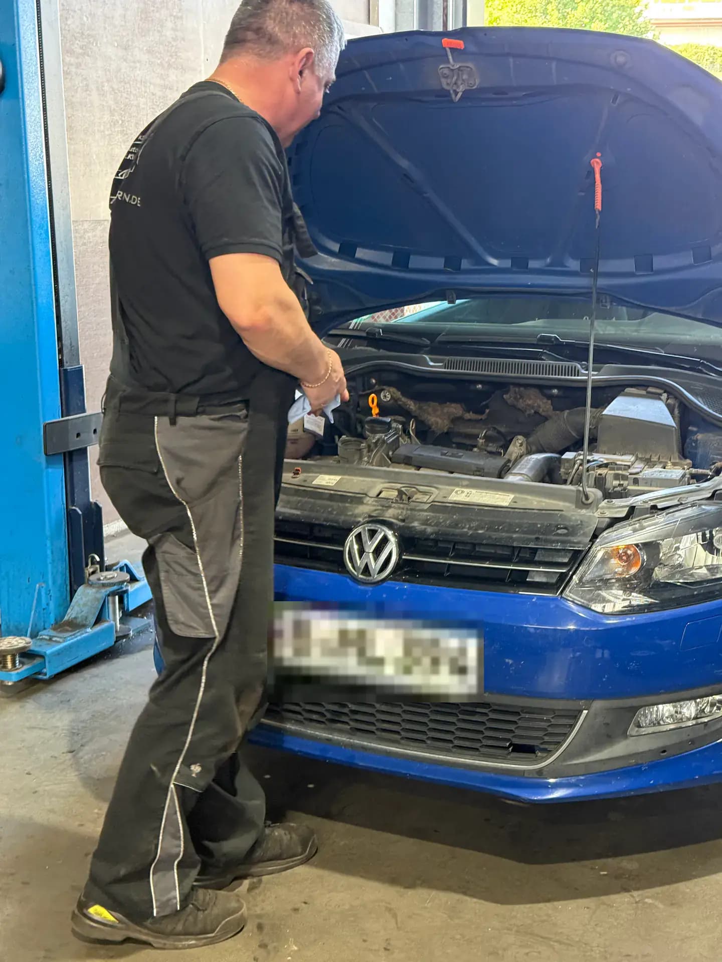 Zbigniew Suchecki am geöffneten Motorraum eines blauen Volkswagen