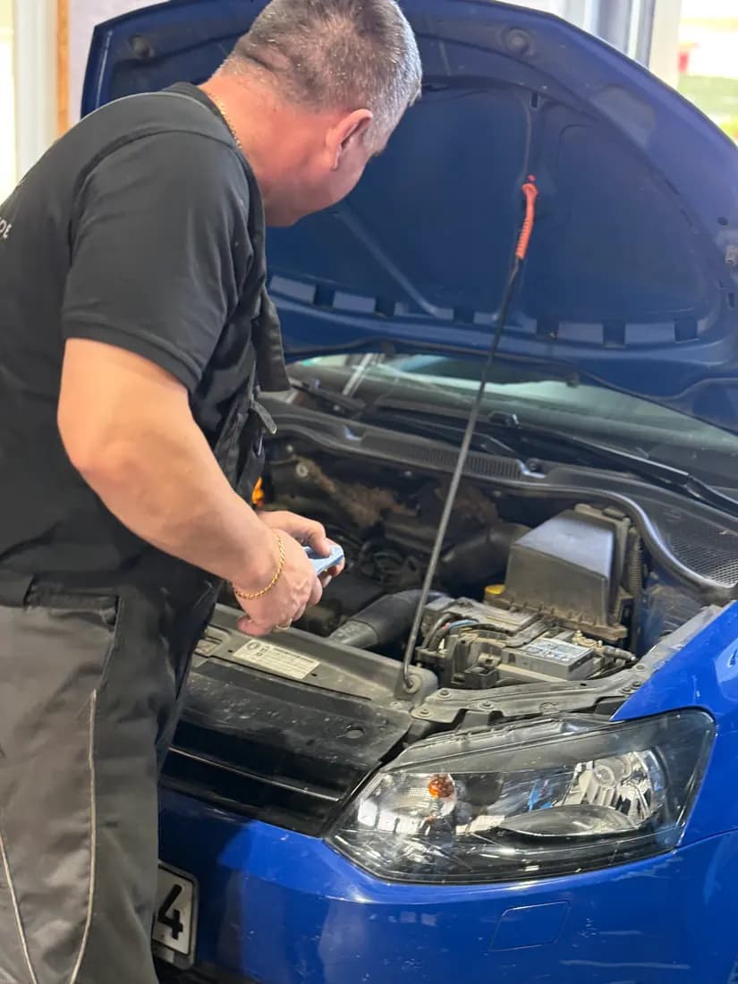 Zbigniew Suchecki bei der Arbeit am Motor eines blauen Volkswagen