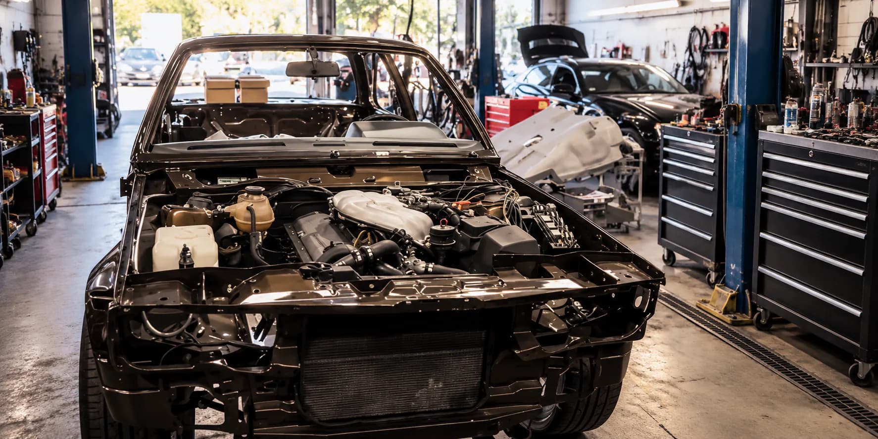 Bis auf die Karosserie zerlegtes Fahrzeug mit offenem Motorraum in der Halle